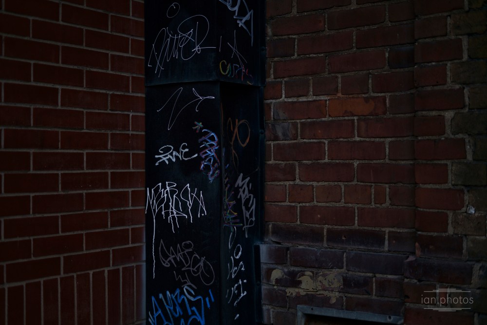 Tagged post near bricked wall.