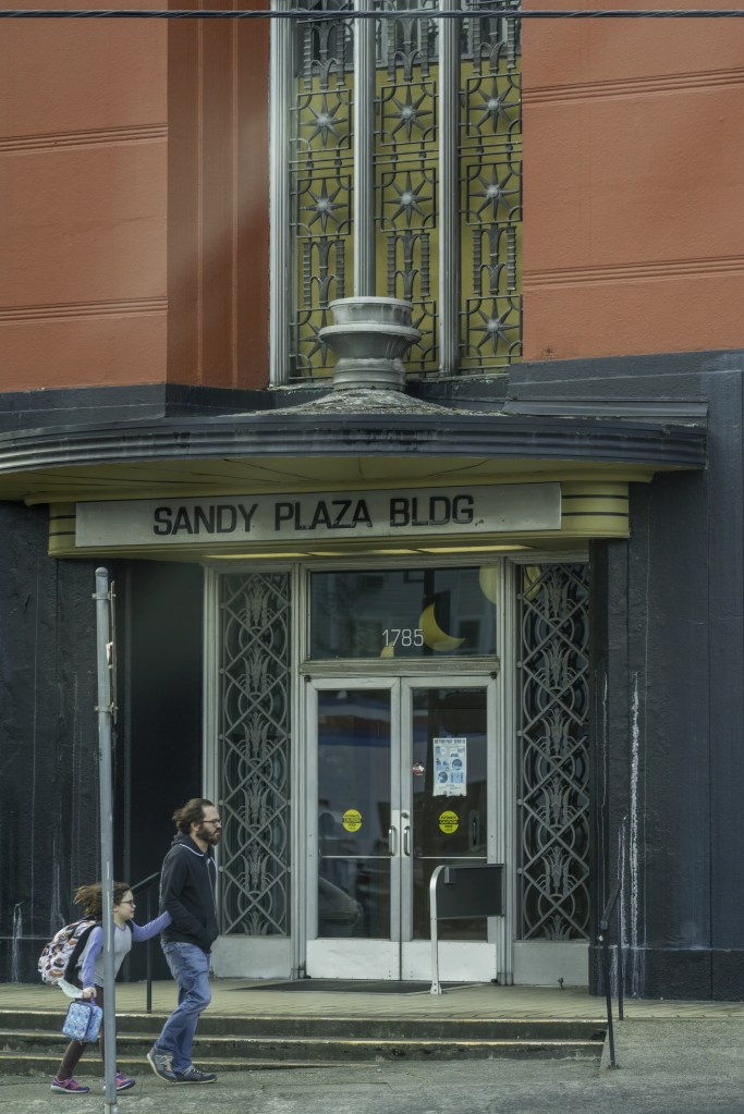 Dad ? and child rushing past the Sandy Plaza Building in Portland OR, Nov 2022
